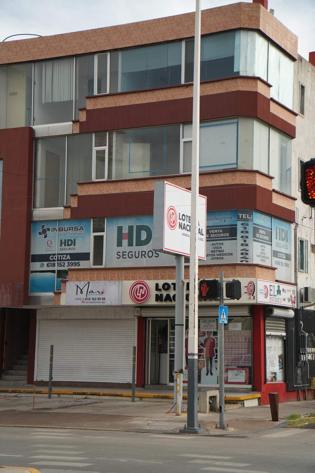 Vista del edificio desde la calle, con los letreros de seguros sobre los locales de planta baja